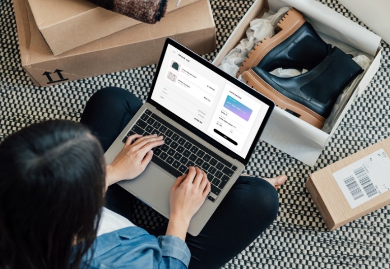 Woman sitting cross-legged with her laptop surrounded by online shopping packages