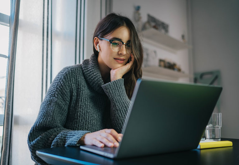 Young woman looking at her laptop with a content expression