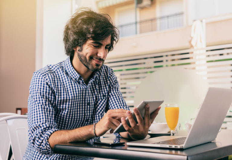 hombre con barba revisa su tablet que sostiene en las manos