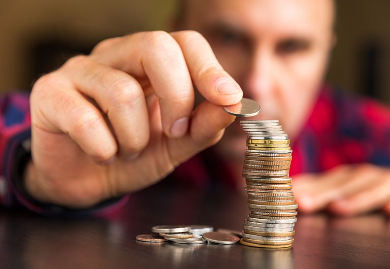 Close-up of man's hand stacking coins